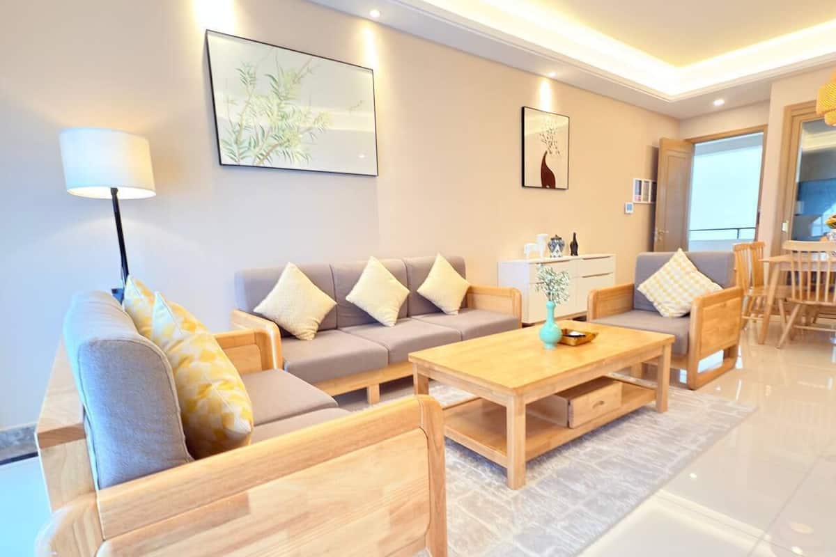 A modern living room with a sofa set, wooden coffee table, and a dining area with a table and chairs.