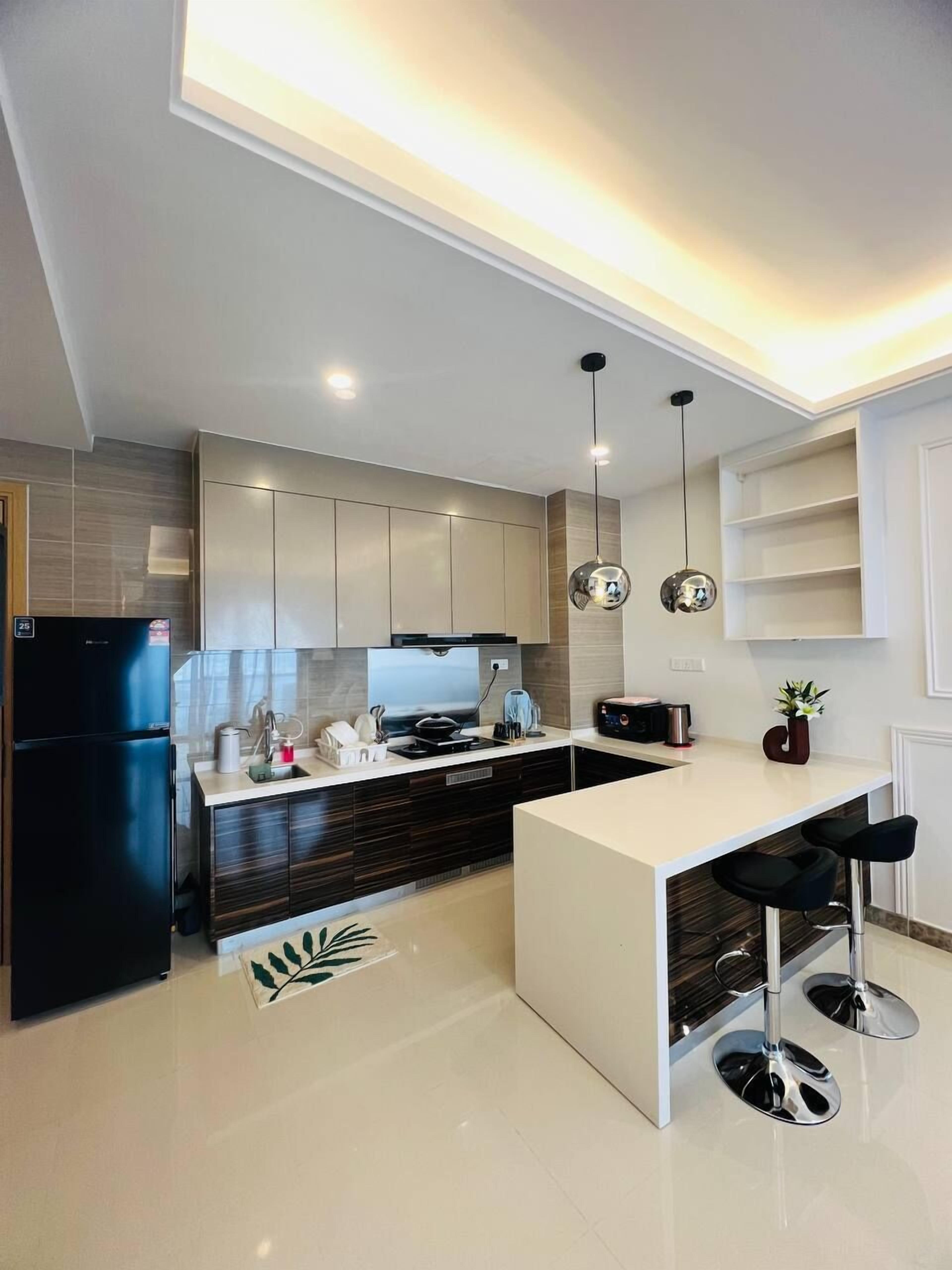 A modern kitchen with a central island, dark cabinetry, and pendant lighting.