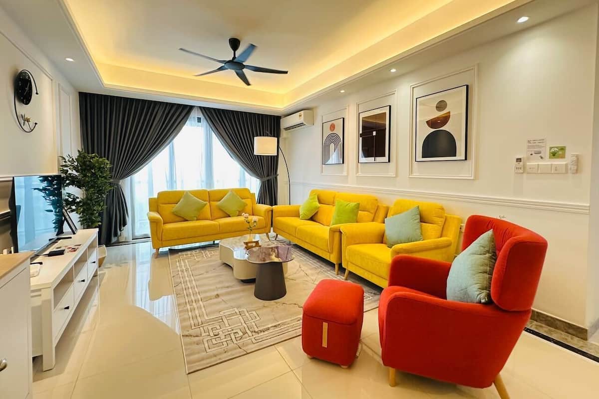 A modern living room with yellow sofas, a red armchair, and a ceiling fan.