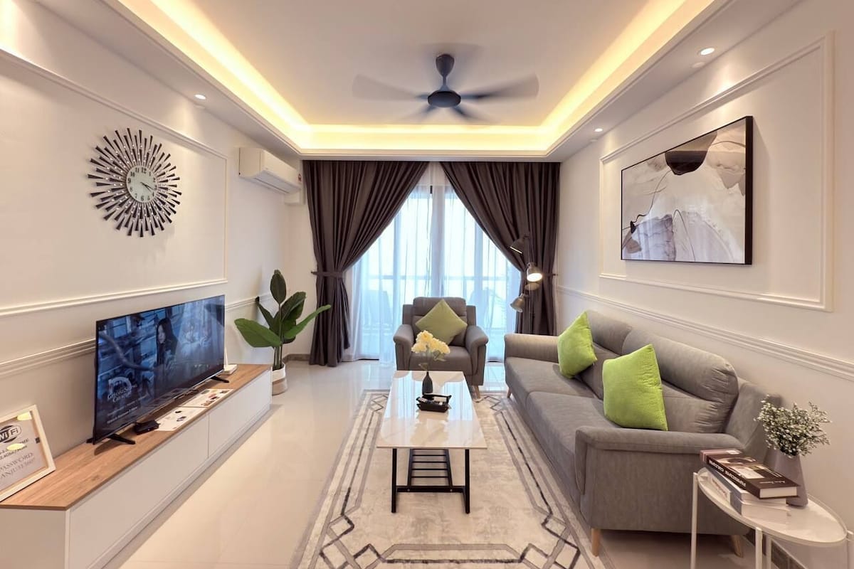 A modern living room with a flat-screen TV, a ceiling fan, and a large window with curtains.