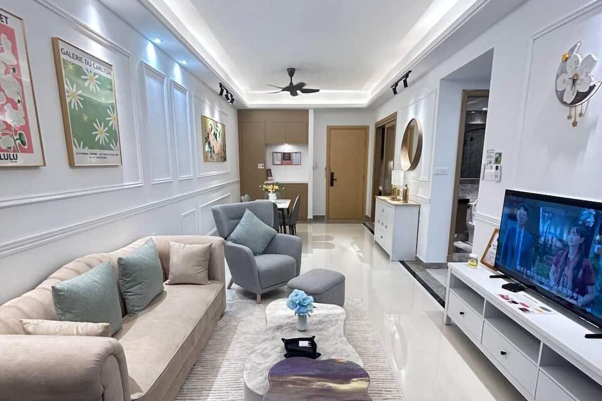 A modern living room with a sofa, armchairs, a coffee table, and a TV.