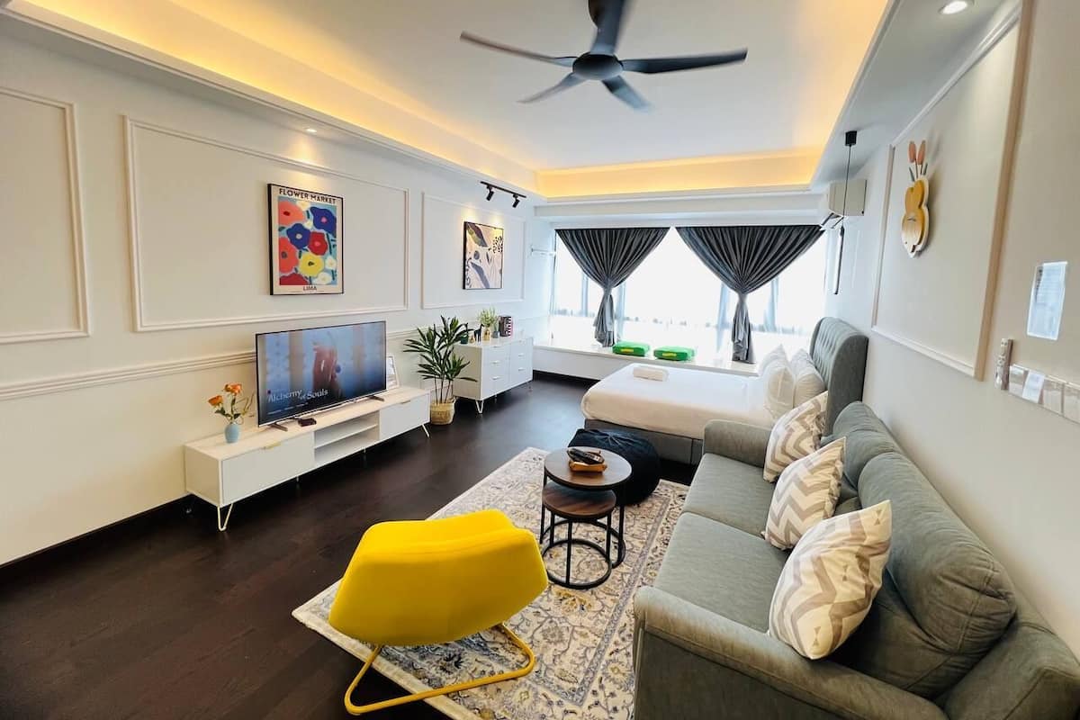 A modern living room with a sofa, a yellow chair, a TV, and a ceiling fan.