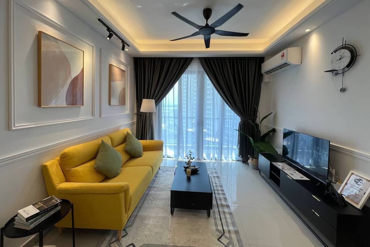 A modern living room with a yellow sofa, a black coffee table, a ceiling fan, and a TV on a black stand.