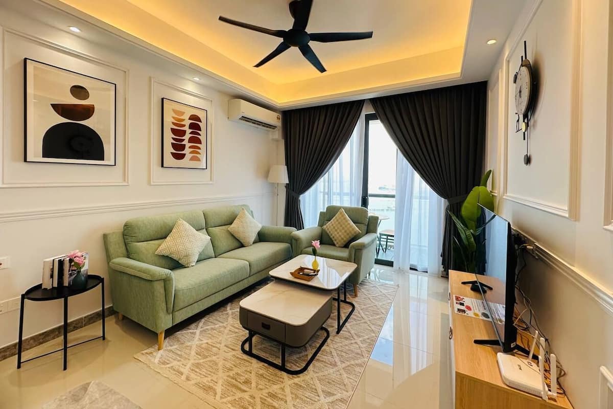 A modern living room with a green sofa, a coffee table, and a TV on a wooden stand.