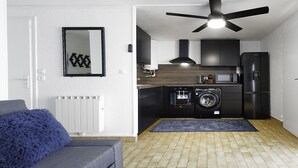 A compact kitchen with a ceiling fan, a washing machine, a microwave, and a refrigerator.