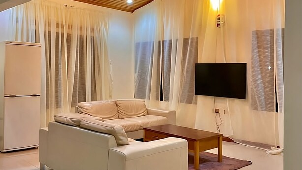 Un salon moderne avec un canapé, une table basse, un téléviseur à écran plat et un ventilateur de plafond.