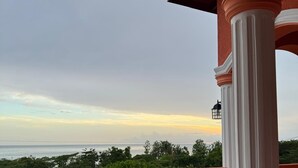 Un balcon avec vue sur la mer et la verdure.