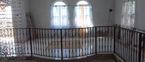 A room with a balcony, arched windows, and a view of the outside.