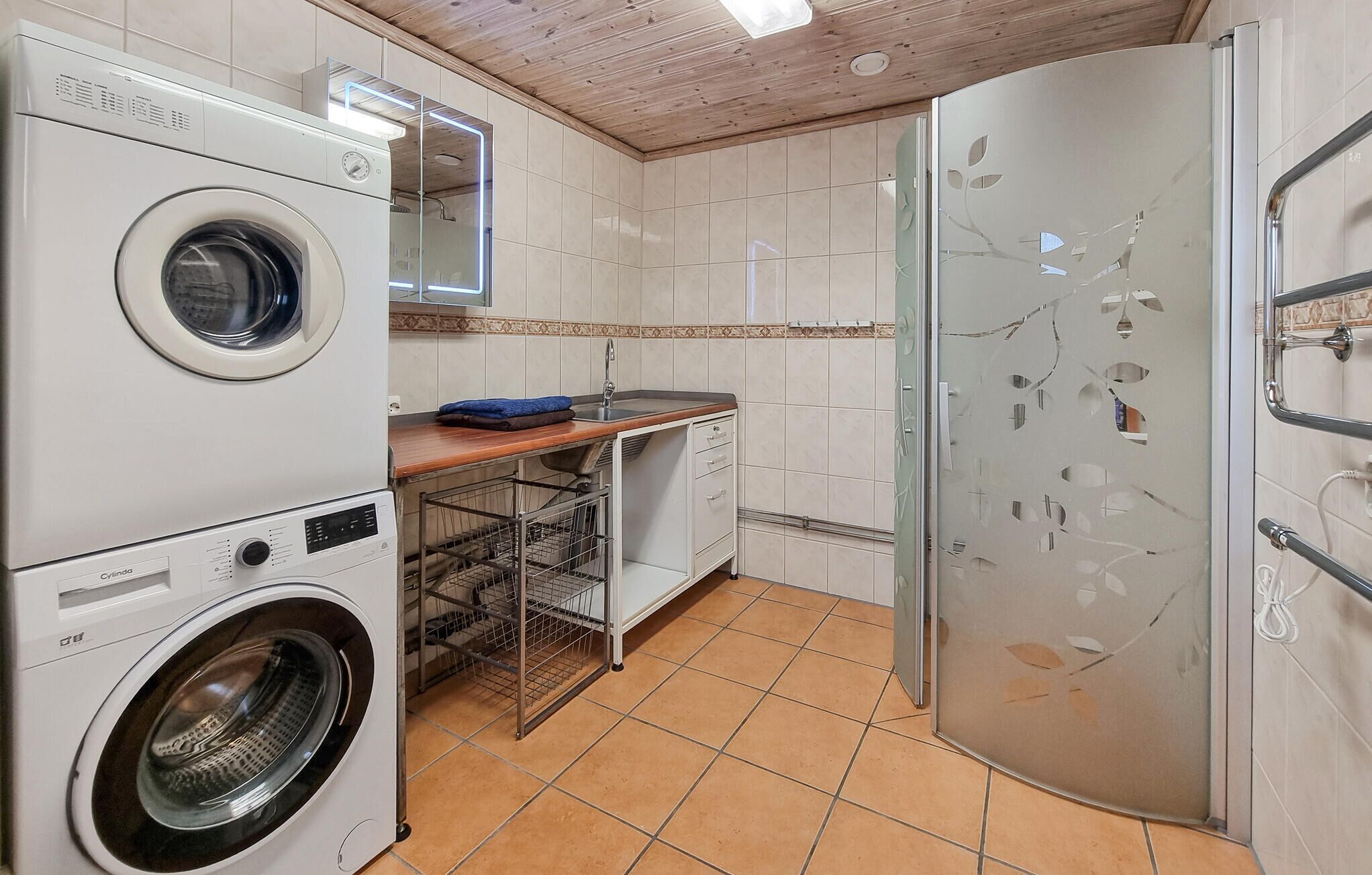 A laundry room with a washing machine, dryer, and a glass-enclosed refrigerator.