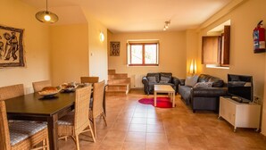 A dining area with a table and chairs, a sofa, a TV, and a fireplace. - Casa Rural en Terminon (Terminon)