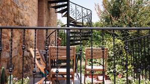 A balcony with wooden chairs, a wrought iron railing, and potted plants. - Casa Rural en Terminon (Terminon)