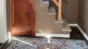 Una escalera con vigas de madera, escalones alfombrados y una puerta al final.
