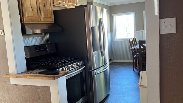 Una cocina compacta con horno integrado, refrigerador de acero inoxidable y armarios de madera.