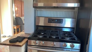 Una cocina con estufa, horno y refrigerador de acero inoxidable.