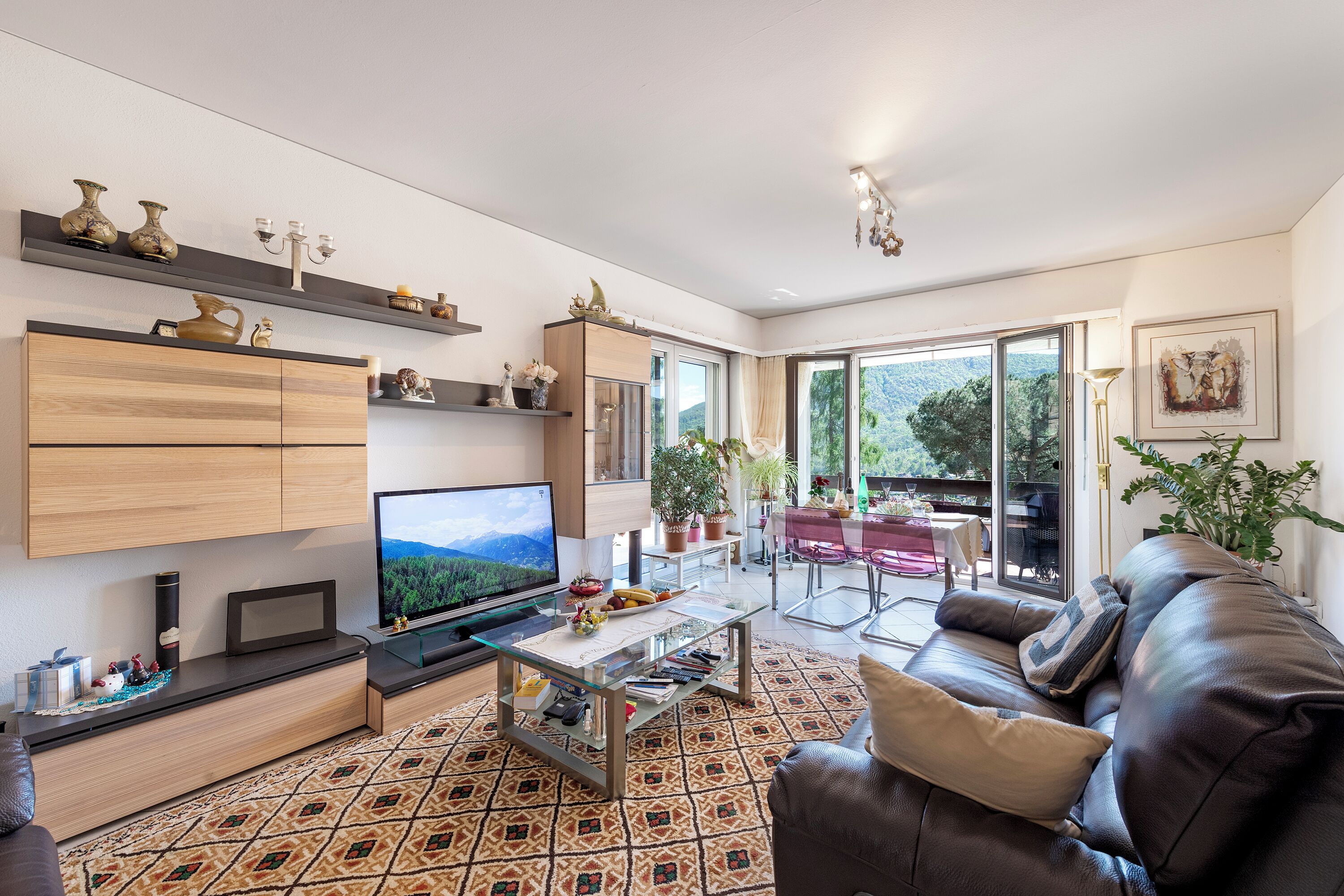 Ein modernes Wohnzimmer mit Flachbildfernseher, Glastisch und Ledersofa.