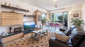 Un salon moderne avec un téléviseur à écran plat, une table basse en verre et un canapé en cuir.