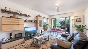Ein modernes Wohnzimmer mit Flachbildfernseher, Glastisch und Ledersofa.