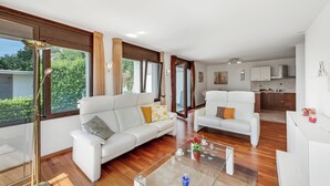 A modern living room with two white sofas, a glass coffee table, and a view of the kitchen. - Vernate Lugano Lake Sweet View (Vernate)