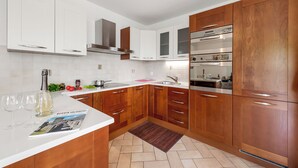 A modern kitchen with white and wooden cabinets, stainless steel appliances, and a central island with a magazine. - Vernate Lugano Lake Sweet View (Vernate)