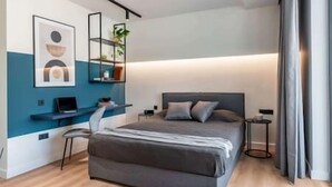 Une chambre à coucher moderne avec un lit, des tables de chevet, un bureau et une chaise.