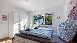 Een slaapkamer met een bed, een raam, een radiator en een witte inbouwkast.