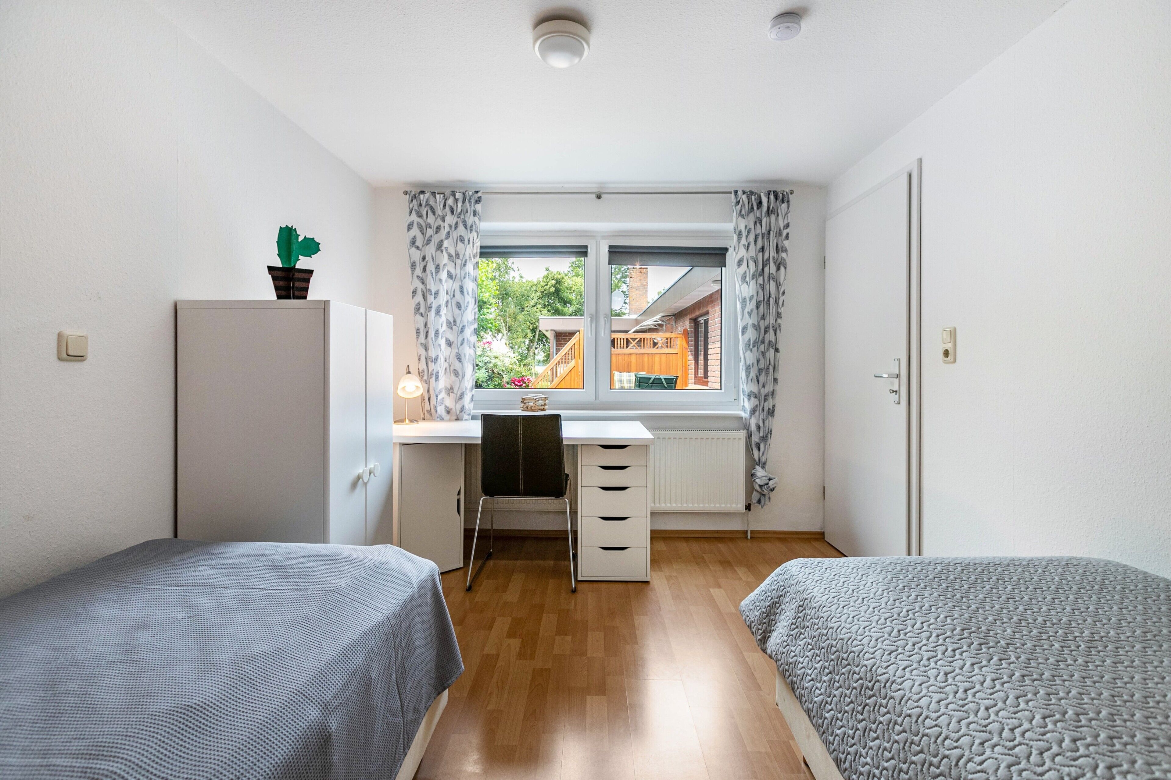 Un dormitorio con dos camas, un escritorio y un radiador.
