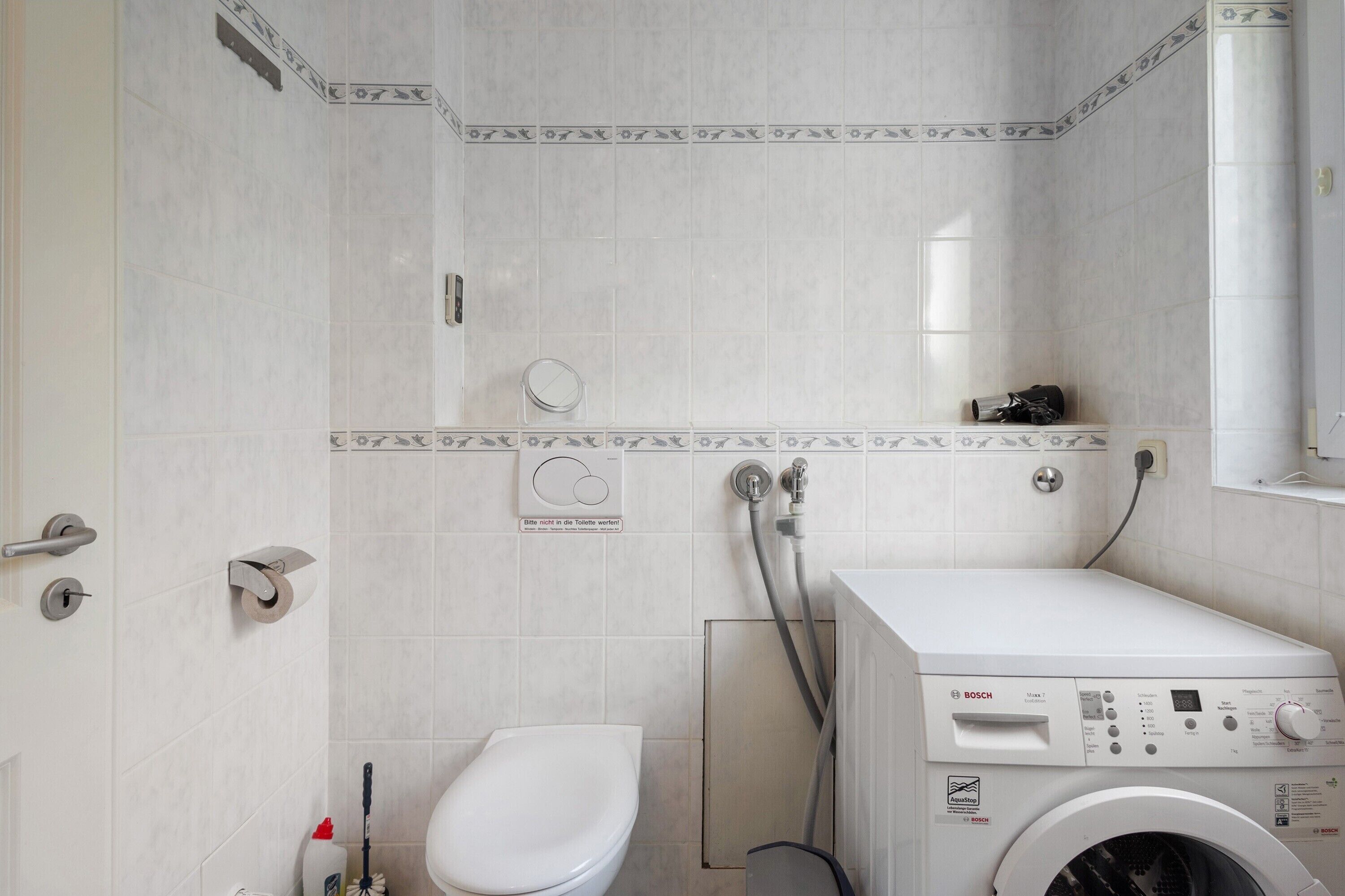 Une salle de bain équipée de toilettes, d’un lave-linge et d’une douche.