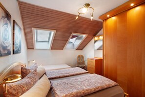 A bedroom with two beds, skylights, a wooden wardrobe, and a bedside table with a lamp. - Haus Schönblick - "Apartment 2" with Mountain View, Balcony and Wi-Fi (Willingen (Upland))