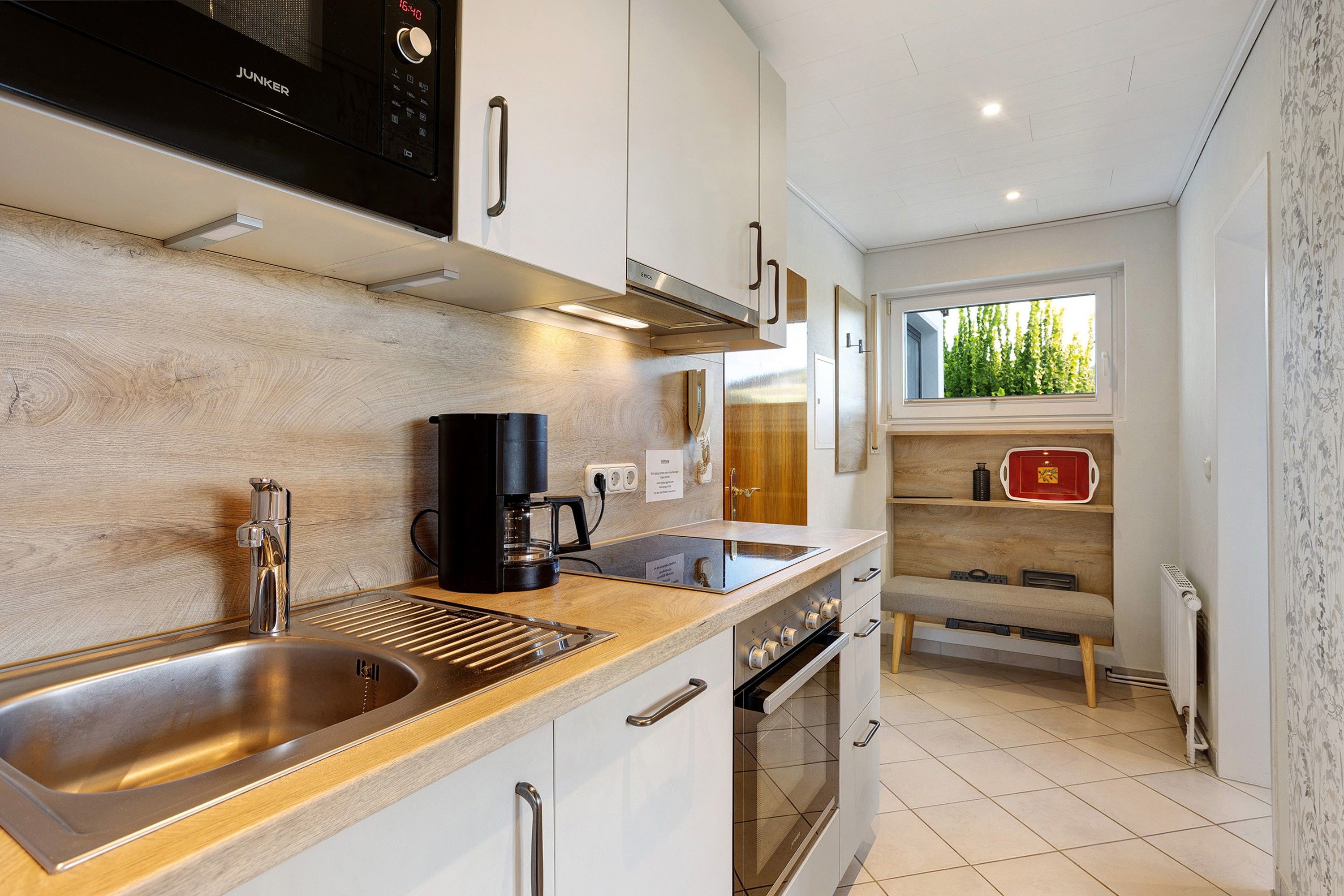 A modern kitchen with a stainless steel sink, a coffee maker, and a built-in oven.