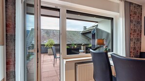 Et moderne værelse med en skydedør til en terrasse, et spiseområde med stole og en radiator.