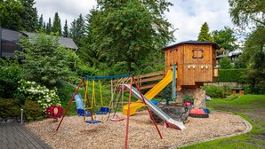 Ein Spielplatz mit Schaukeln, Rutschen und einer hölzernen Kletterkonstruktion.