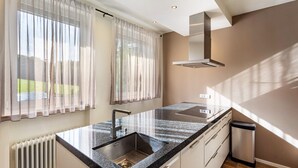 A modern kitchen with a granite countertop, stainless steel sink, and a range hood.