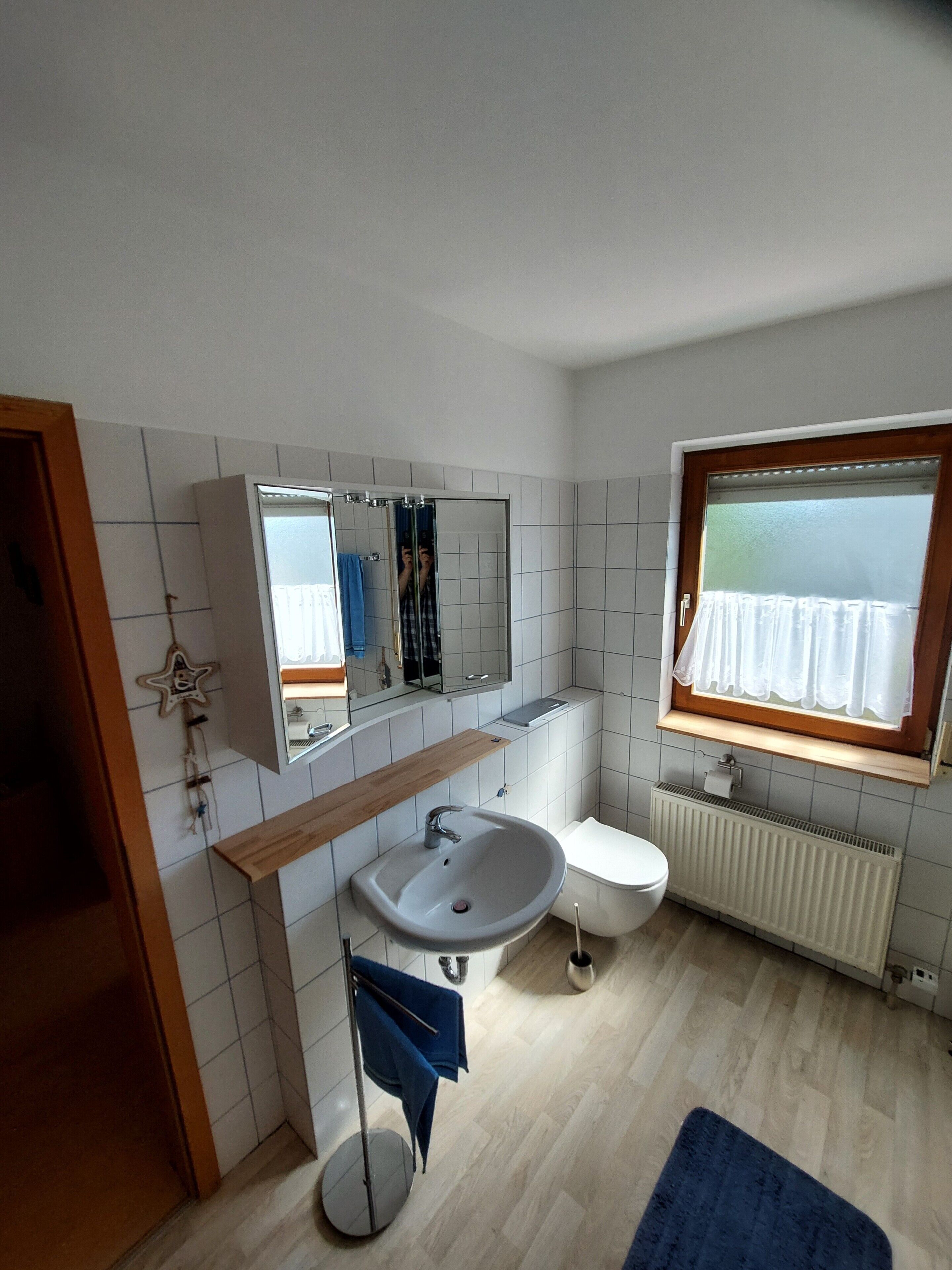 Ein modernes Badezimmer mit Waschbecken, Spiegel und Fenster.