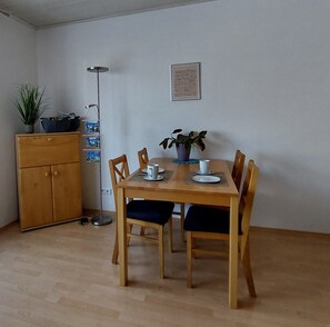 A dining area with a wooden table, four chairs, a cabinet, a floor lamp, and two potted plants. - Apartment 'Lipperland' with Balcony and Wi-Fi (Detmold)