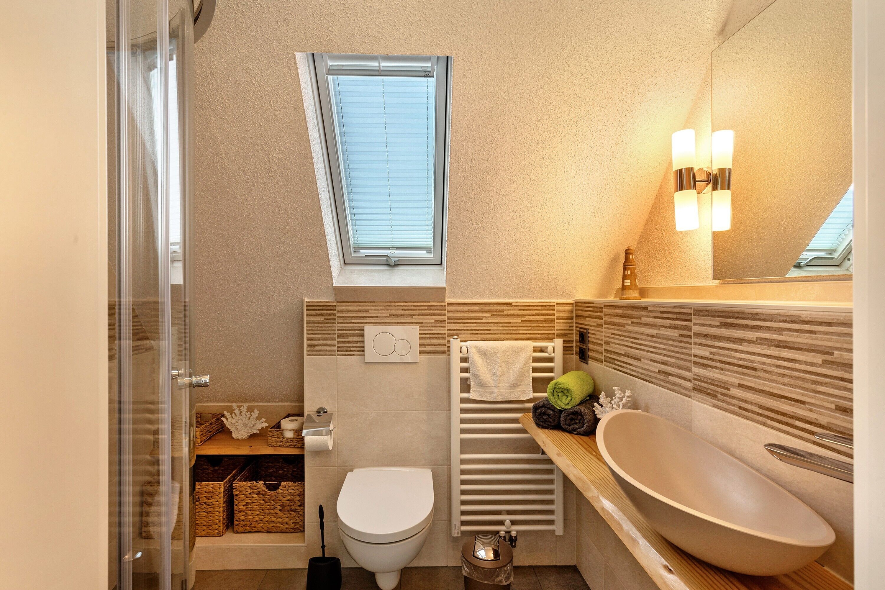A modern bathroom with a toilet, bidet, vanity with a sink, and a window.