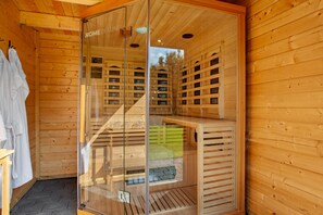 Un sauna de madera con puertas de vidrio, un banco y un perchero para toallas.