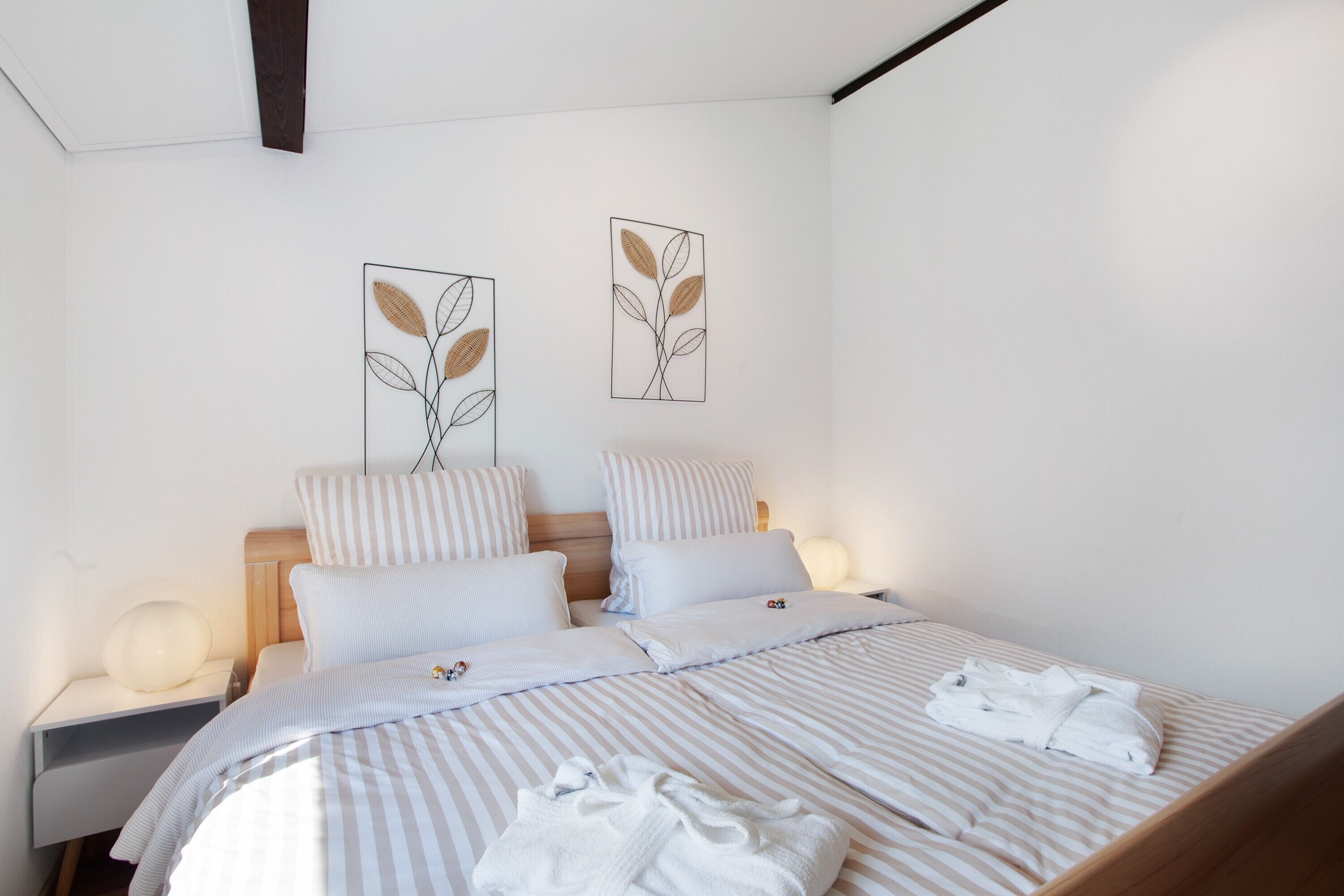 A neatly made bed with striped bedding, two pillows, and a folded towel on the bed.