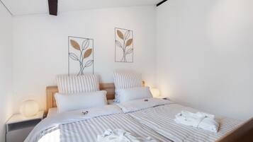 A neatly made bed with striped bedding, two pillows, and a folded towel on the bed.