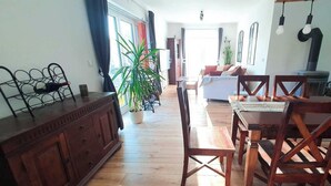 Un vaste espace de vie comprenant une table à manger en bois, des chaises, un canapé et une grande plante en pot.