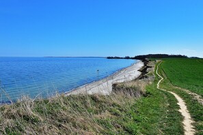 Un sentier côtier longeant une étendue d’eau, avec un ciel dégagé.