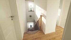 Un escalier avec des rampes en bois, une petite plante en pot et une fenêtre avec un rideau.