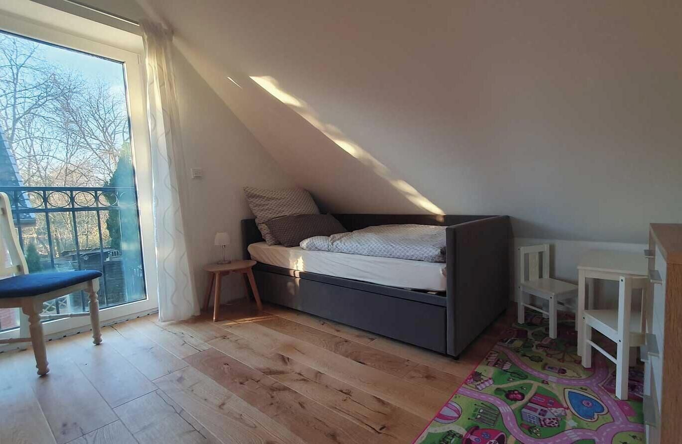 Une chambre avec un lit en mezzanine, une petite table, une chaise et un tapis coloré.