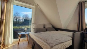Une chambre à coucher avec un lit, une petite table et une fenêtre avec des rideaux.