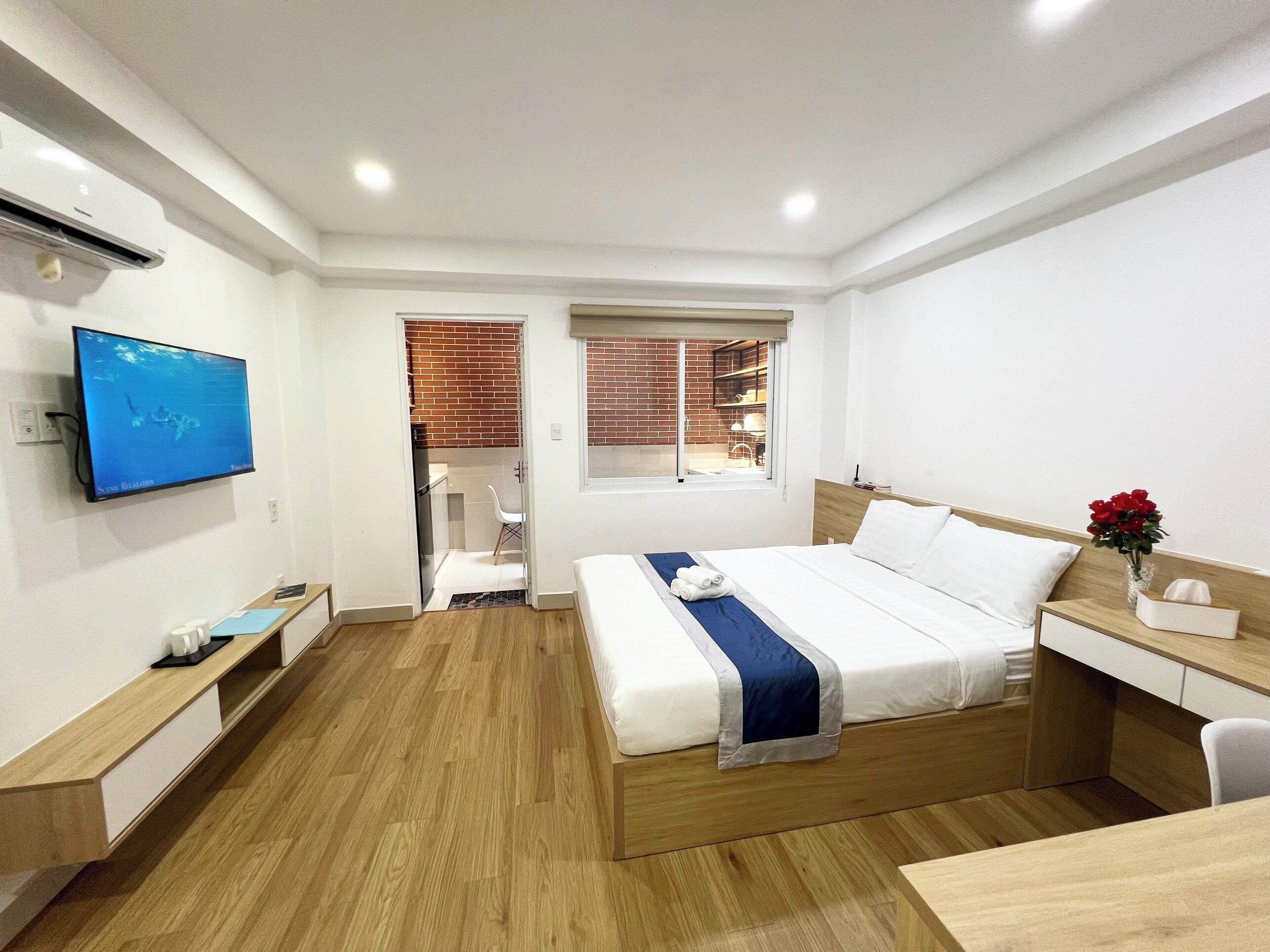 Quarto de hotel moderno com cama, mesa de cabeceira, televisão e vista para o exterior.