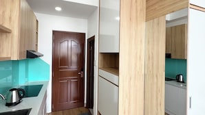 A compact kitchen with wooden cabinets, a built-in bench, and a door leading to another room.