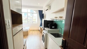 A modern kitchen with white cabinets, a washing machine, and a microwave.