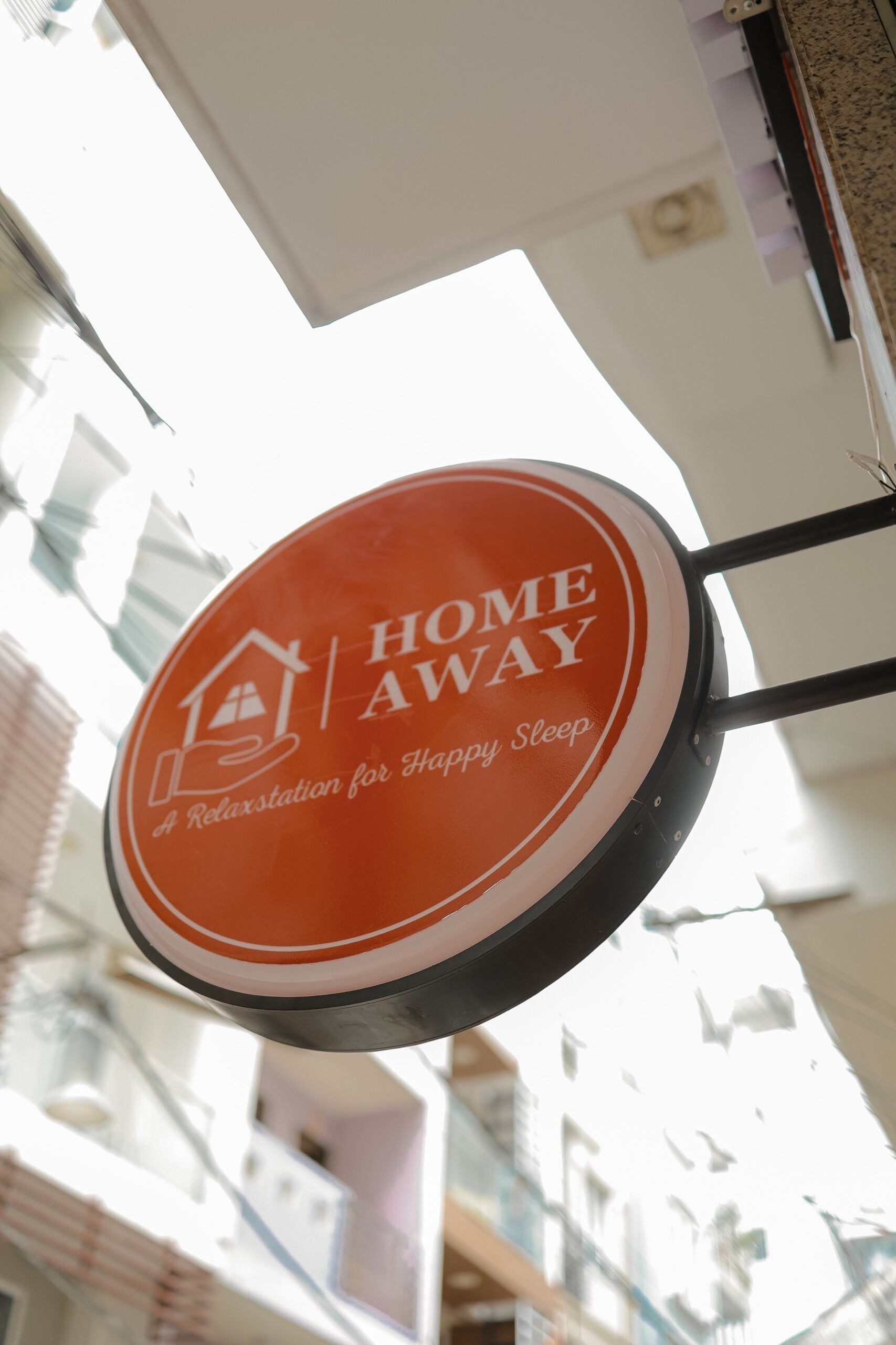 Un panneau circulaire avec le texte « HOME AWAY » et « A Relaxation for Happy Sleep » sur un fond blanc.