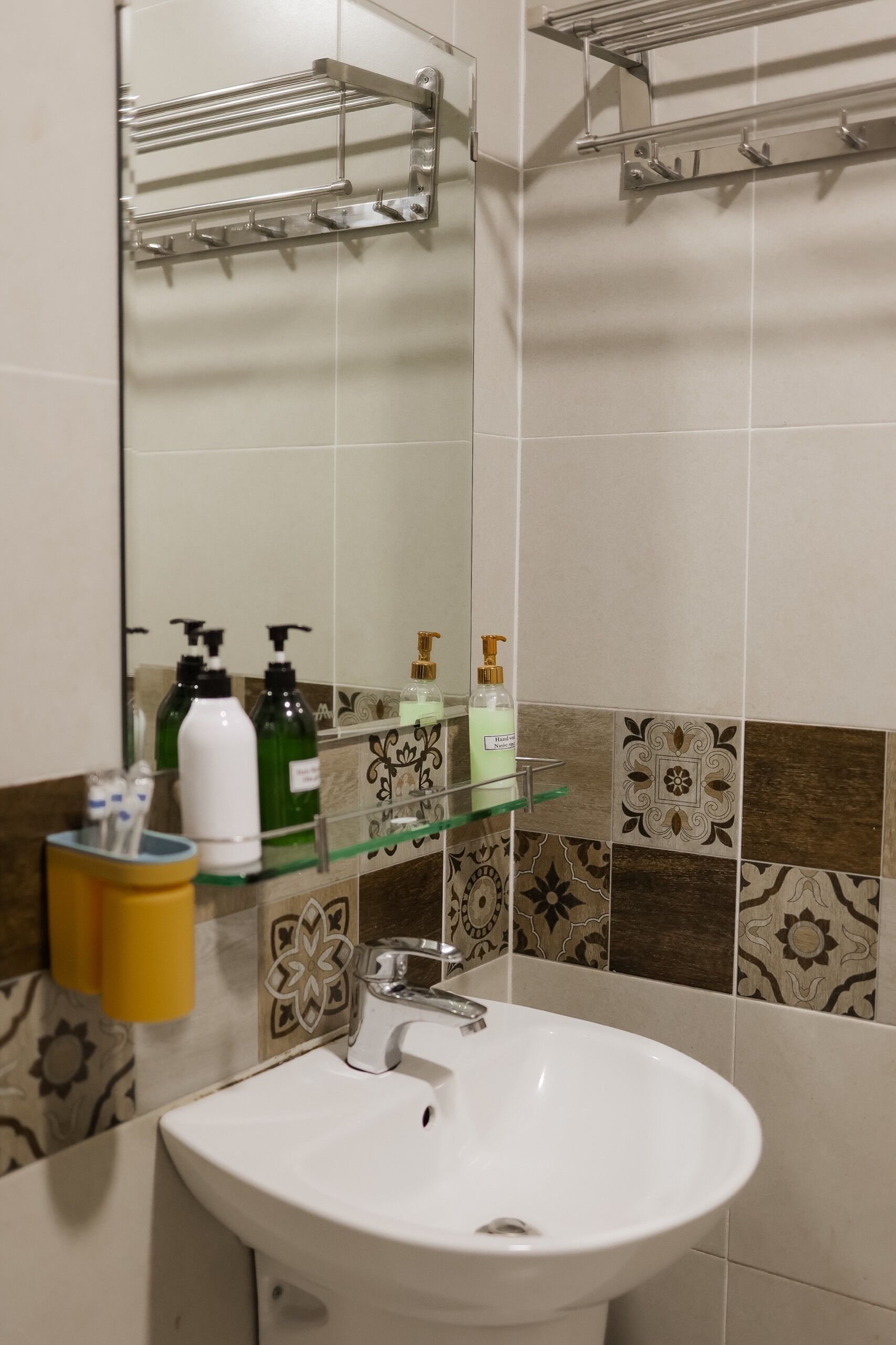A bathroom with a white sink, a mirror, and a glass shelf holding toiletries.