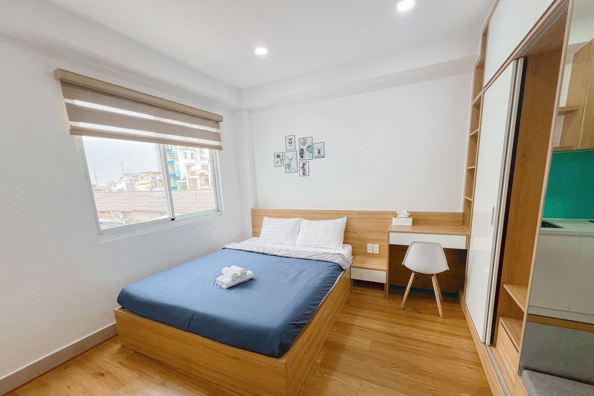 Quarto com cama de madeira, uma escrivaninha e uma cadeira.