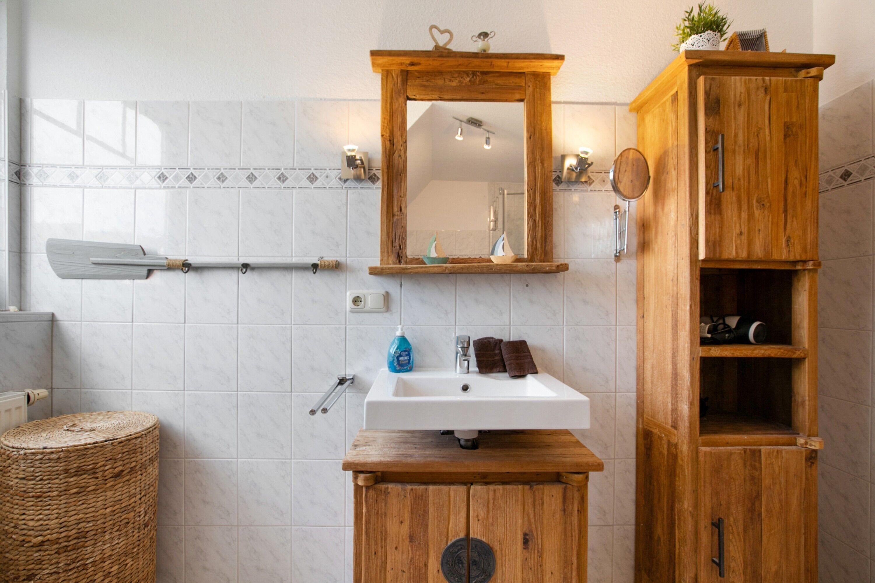 A bathroom with a wooden cabinet, a white sink, and a mirror.
